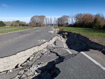 Een asvaltweg met een grote breuk in het midden door een aardbeving