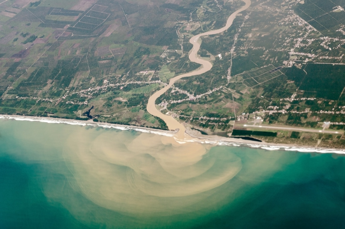 Een supermodderige rivier vertroebelt de kraakheldere zee met zijn zand en klei.