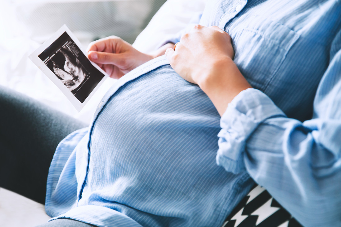 Een zwangere vrouw kijkt naar een echo foto van haar baby.