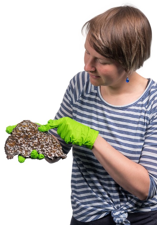 Arike pakt een meteoriet met handschoenen. Zo roest het ijzer in de meteoriet niet door het vocht aan haar handen.
