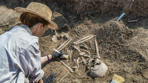 Een foto van een archeoloog die een menselijk skelet opgraaft.