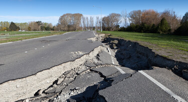 Een asvaltweg met een grote breuk in het midden door een aardbeving
