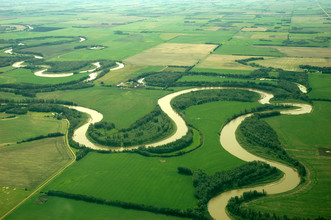 Een modderige rivier meandert over het vlakke land. 